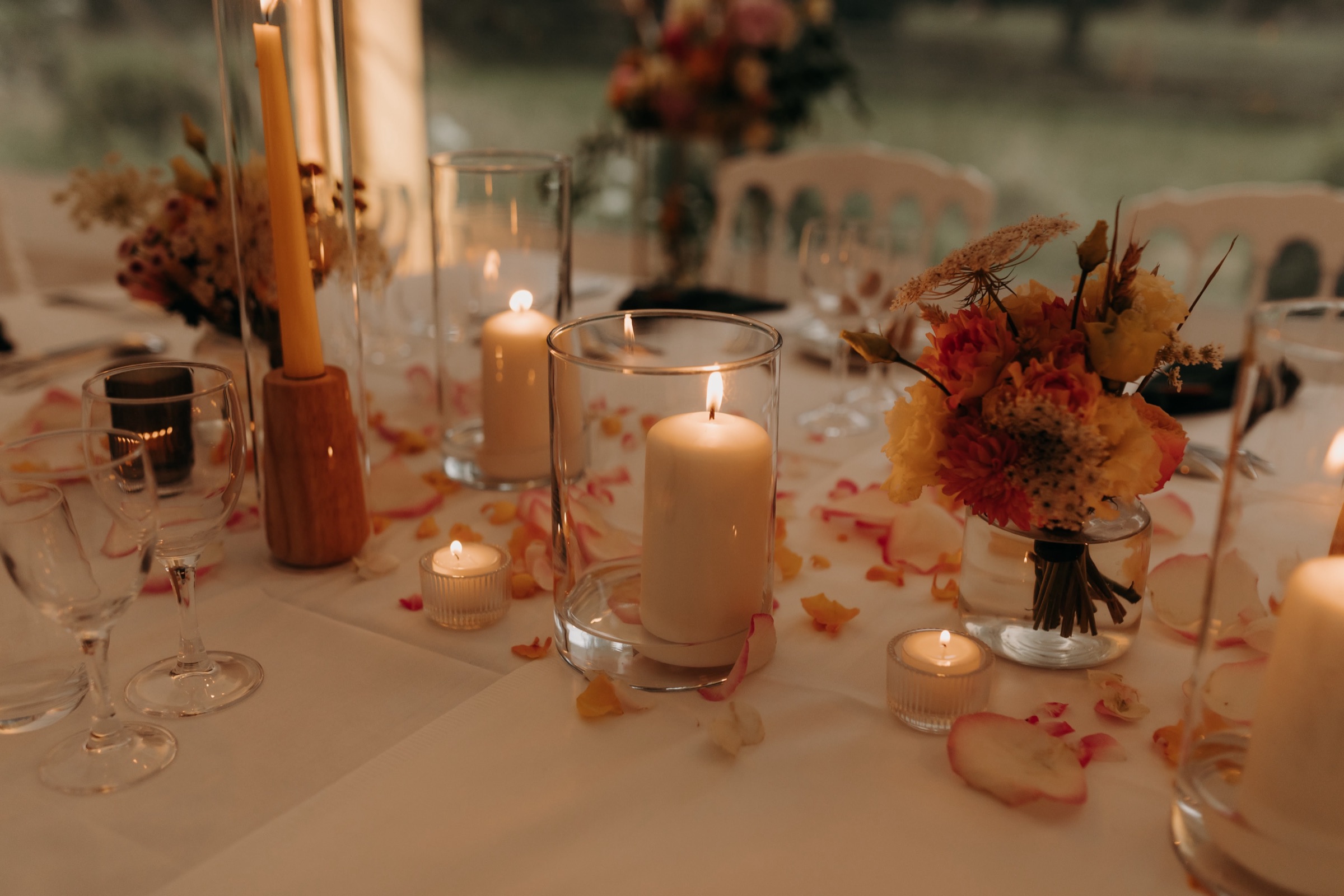 Table de réception dressée à la lumière des bougies, avec bouquet et pétales de rose